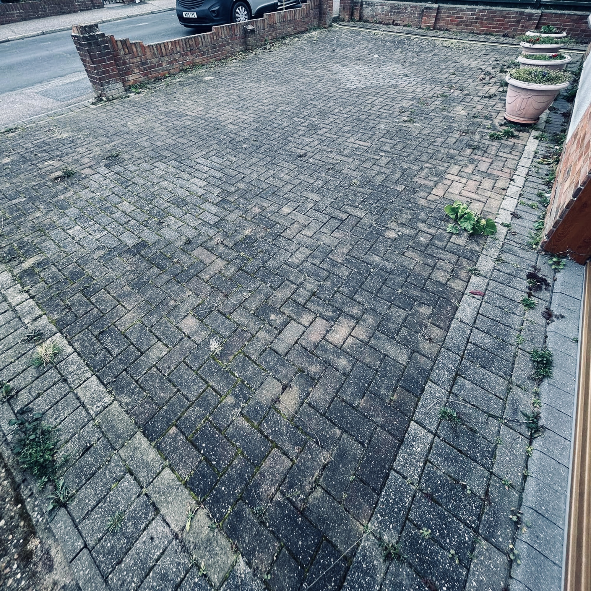 Driveway before restoration - heavily soiled, moss-covered grey block paving